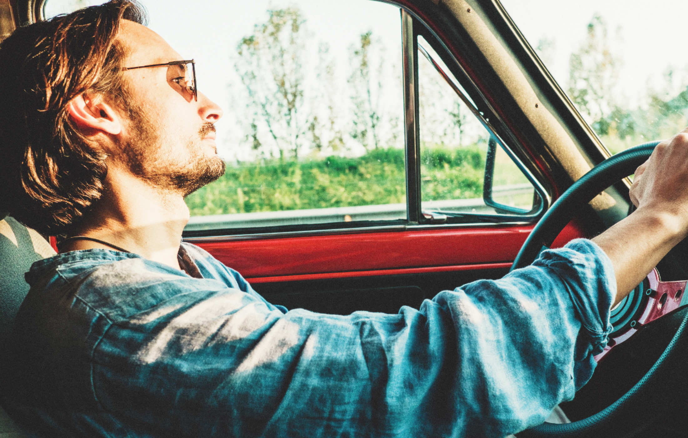 サングラスをかけた1人の男性が車を運転している様子